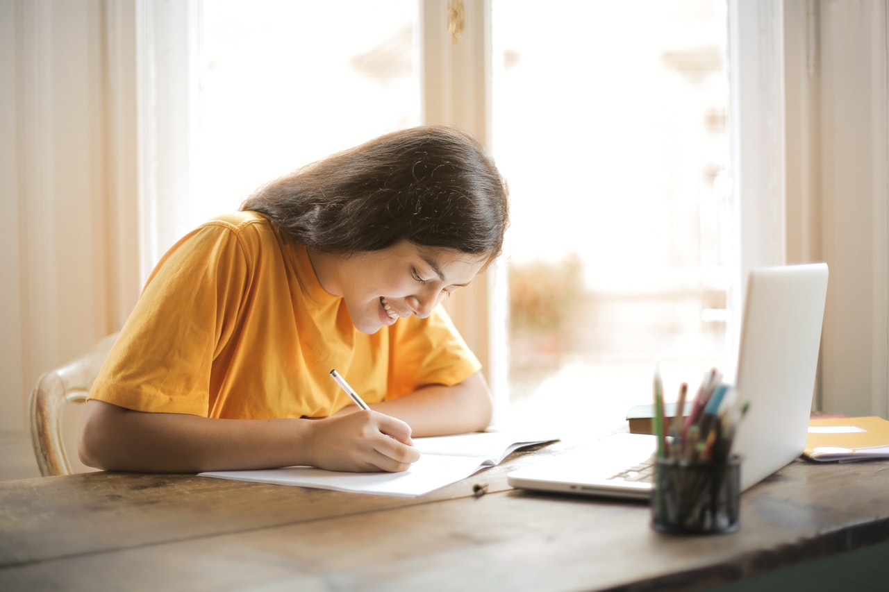 Young female student studying her chatsifieds english exam in front of laptop