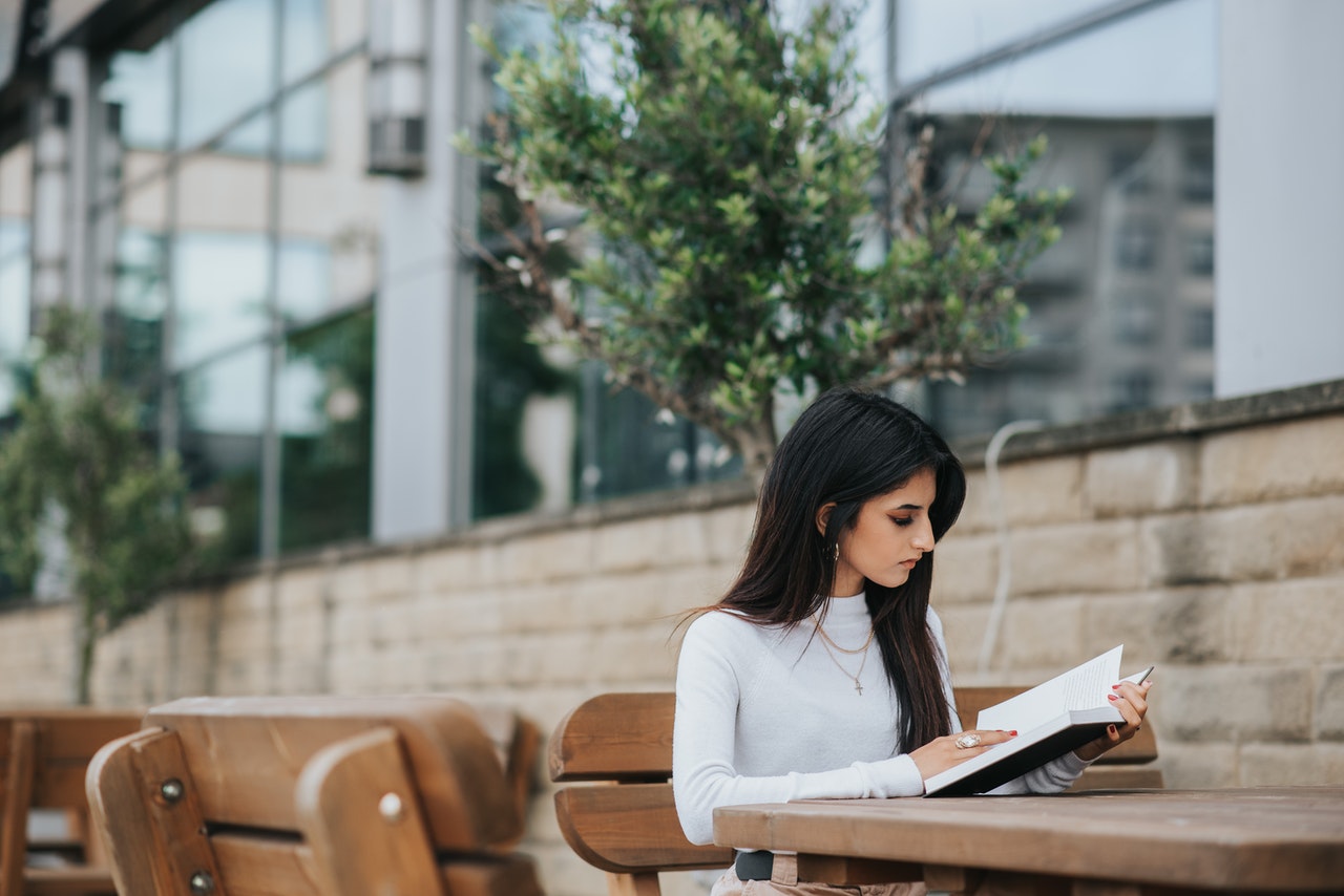 young female student study her chatsifieds english exam on a garden table