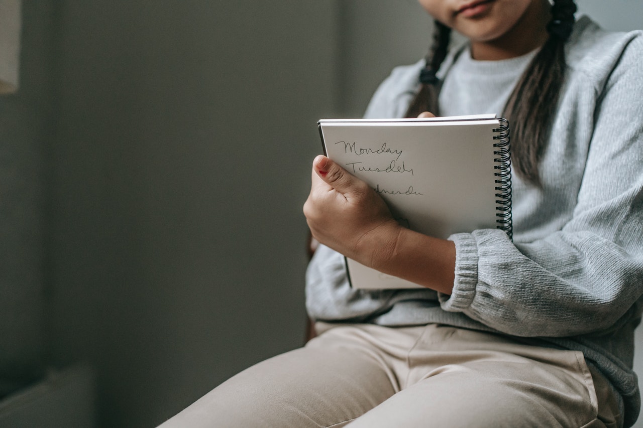A girl holding a notepad to study for chatsifieds english exam